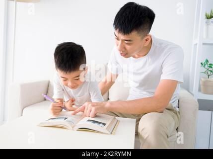 Padre che aiuta il figlio a fare i compiti a casa Foto Stock