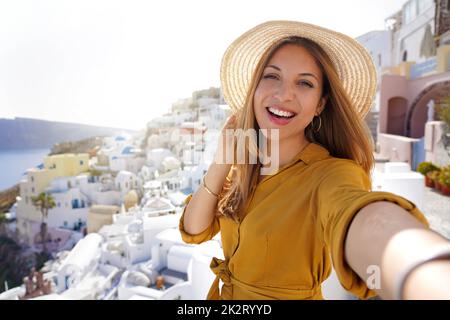 Donna di moda ispanica esuberante che si diverte a prendere autoritratto al tramonto a Santorini Island, Grecia Foto Stock