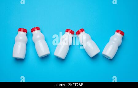 Bottiglie in plastica bianca con tappi rossi per latticini su sfondo blu, vista dall'alto Foto Stock