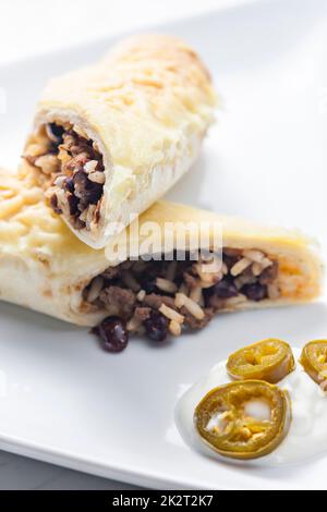 burrito di manzo con riso e fagioli servito con panna montata e jalapenos Foto Stock