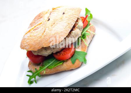 hamburger di tacchino fatto in casa con pomodori ciliegini e rucola in ciabatta Foto Stock