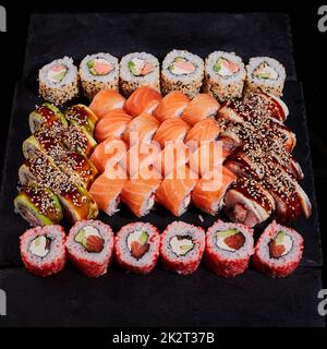 Diversi tipi di rotoli con ripieni diversi sono serviti quadrati su un piatto su sfondo di pietra. Foto Stock
