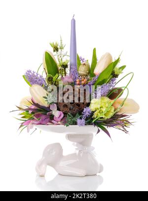 Un vaso stand, un coniglietto bianco contiene una composizione di fiori. Foto Stock