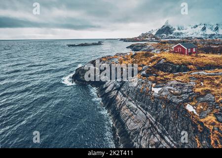 Clif con tradizionale rosso rorbu casa sulle Isole Lofoten in Norvegia Foto Stock