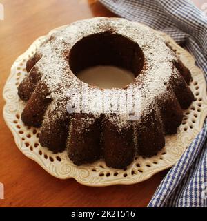 Torta al cioccolato cosparsa di zucchero in polvere su un piatto fondo bianco Foto Stock