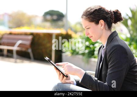 Donna d'affari che usa un tablet seduto su una panca Foto Stock