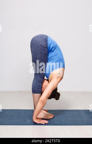 Donna fare yoga asana Uttanasana - permanente di piegare in avanti Foto Stock