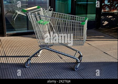 Carrello per prodotti alimentari in piedi vicino all'ingresso del supermercato sulla strada Foto Stock