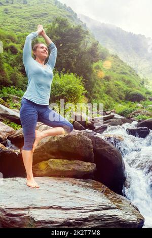 La donna a Yoga asana Vrikshasana posizione dell'albero a cascata all'aperto Foto Stock