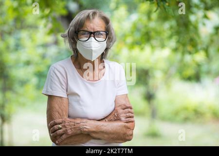 Donna anziana che indossa una maschera protettiva contro i virus Foto Stock