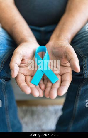 Uomo anziano che tiene un nastro blu di consapevolezza del cancro Foto Stock