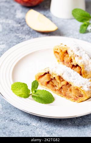 strudel di mela aromatizzato in casa in un piatto su uno sfondo grigio cemento con spazio per il testo Foto Stock