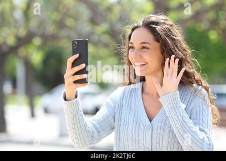 Buona donna che saluta al telefono in una videochiamata Foto Stock