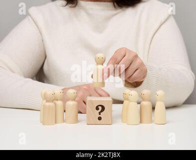 La donna mantiene la statuetta rossa di legno separata dal gruppo. Concetto di crescita della carriera, persona unica. Foto Stock