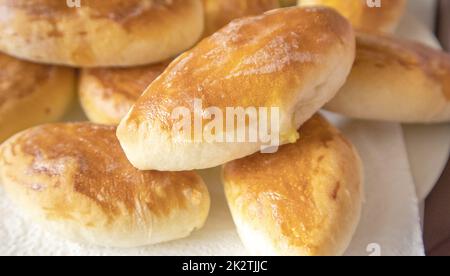 Un sacco di deliziose torte calde appena sfornate con ripieno, cibo di sottofondo, primo piano, cucina russa Foto Stock