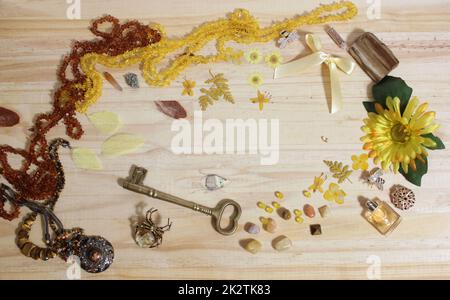 Gioielli gialli e marroni e decorazioni con chiave in ottone d'epoca sulla tavola in legno Foto Stock