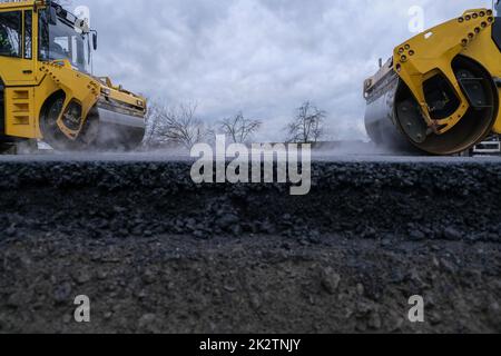 Vista ravvicinata di un rullo stradale che lavora su un nuovo cantiere stradale. Foto Stock