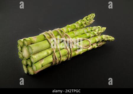 Asparagi verdi legati con corda di iuta su un nero Foto Stock