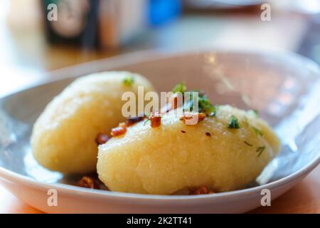 Il piatto nazionale della Lituania - gnocchi di patate, zepeline con verdi e cracklings in un piatto Foto Stock