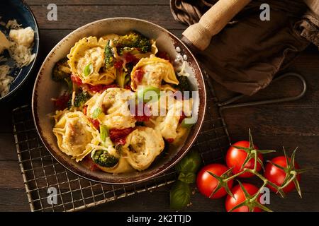 Padella con tortelloni cotti con verdure su griglia metallica Foto Stock