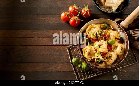 Tortelloni in padella sulla griglia vicino agli ingredienti Foto Stock