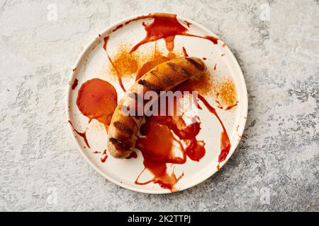 Salsiccia di maiale fritta condita con curry e ketchup Foto Stock