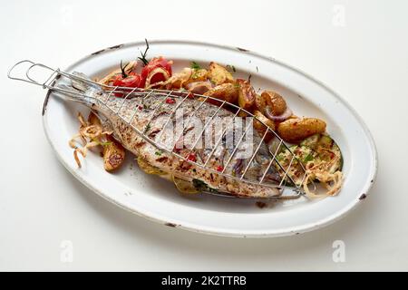 Pesce alla griglia e verdure con patate poste su piatto bianco Foto Stock