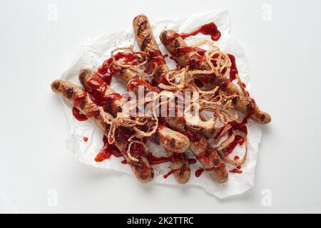 Salsicce alla griglia e cipolle servite con salsa Foto Stock