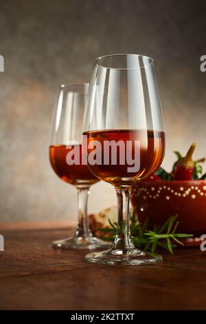 Wineglasses di sherry contro lo sprig del rosmarino sul tavolo Foto Stock