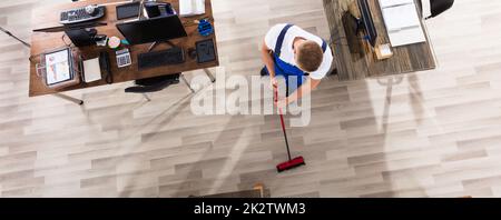 Bidello di piano di pulizia con la scopa in ufficio Foto Stock