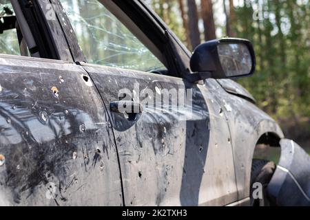 Una macchina di civili sparata dagli invasori durante la guerra in Ucraina. Incidente stradale o incidente, incidente stradale. Buchi di shrapnel corpo della vettura. Atrocità dell'esercito russo. Foto Stock