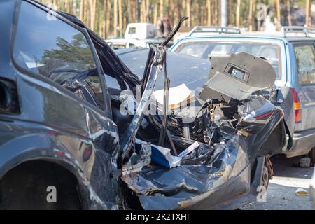 Molte auto rotte dopo un incidente stradale nel parcheggio di una stazione di riparazione sulla strada. Officina per danni alla carrozzeria all'aperto. Vendita di auto di assicurazione all'asta. Foto Stock