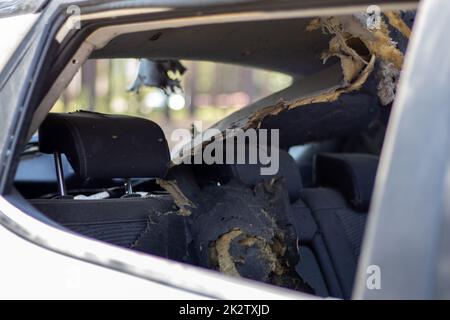 Una vettura dopo un incidente con un cristallo posteriore e laterale rotto, vista dal finestrino posteriore. Finestrino rotto in un veicolo. Il relitto della berlina, una vista dettagliata ravvicinata della vettura danneggiata. Foto Stock