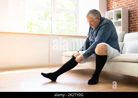 Uomo che mette sulle calze mediche di compressione Foto Stock
