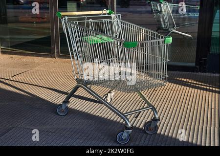 Carrello per prodotti alimentari in piedi vicino all'ingresso del supermercato sulla strada Foto Stock