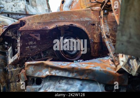 Auto rotte e bruciate nel parcheggio, incidente o vandalismo deliberato. Auto bruciata. Conseguenze di un incidente stradale. Danneggiato da incendio. Discarica di veicoli civili sparati dalle truppe russe in Ucraina. Foto Stock