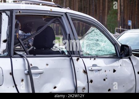 Auto piena di proiettili. Guerra della Russia contro l'Ucraina. Un'auto di civili sparata dall'esercito russo durante l'evacuazione di donne e bambini. Tracce di pallottole e frammenti di conchiglie. Foto Stock