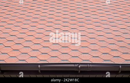 Nuovo tetto con scandole rosse. Tegole sul tetto della casa. Utilizzare per pubblicizzare la fabbricazione e la manutenzione del tetto. Texture macchiata. Copertura conveniente. Foto di alta qualità con spazio di copia. Foto Stock