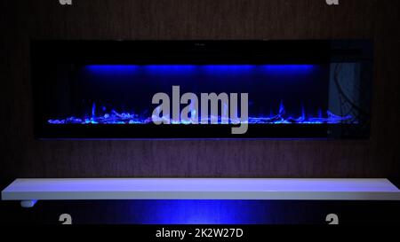 vista su camino elettrico con fiamma artificiale scintillante, arredamento per l'interno, fiamma blu su cristalli Foto Stock