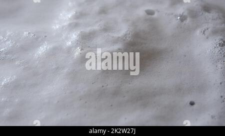 Vapore o nubi di vapore che sorgono dall'acqua bollente con schiuma e bolle coagulate Foto Stock