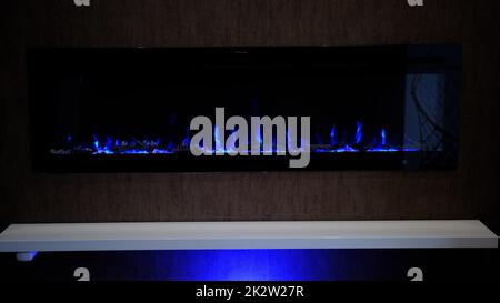 vista su camino elettrico con fiamma artificiale scintillante, arredamento per l'interno, fiamma blu su cristalli Foto Stock