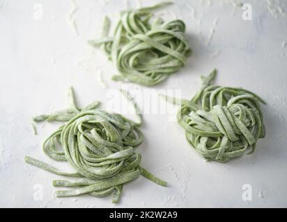 Spinaci crudi fatti in casa. Fettuccine pasta cruda. Nido di tagliatelle verdi. Foto Stock
