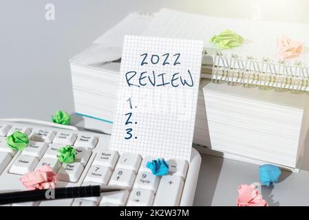 Visualizzazione concettuale 2022 Revisione. Parola per vedere gli eventi importanti o le azioni che hanno reso l'anno precedente la signora nella penna di tenuta del vestito simbolizzando le realizzazioni riuscite del lavoro di squadra. Foto Stock