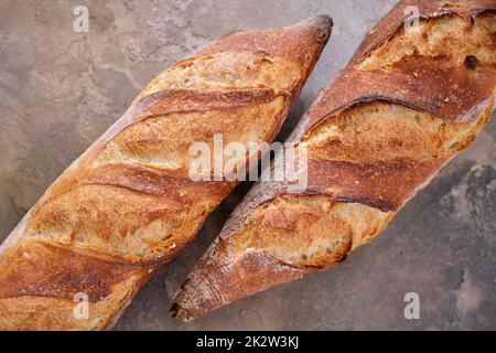 Due baguette appena sfornate su sfondo di pietra. Foto Stock