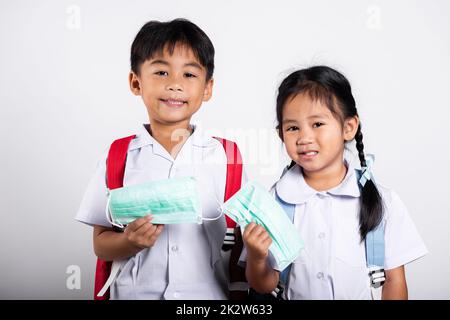 Due studenti asiatici ragazza ragazzo fratello ragazzo fratello indossare studente tailandese uniforme tenere maschera di protezione pronto per andare a scuola Foto Stock