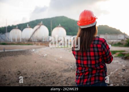 Donna operatrice asiatica felice nell'industria chimica del petrolio lavoratore di ispezione visiva elenco di lavoro sulla clipboard in pianta Foto Stock