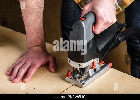 Uomo con sega elettrica a maschera per tagliare legno Foto Stock