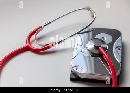 Stetoscopio rosso con unità disco rigido interna hdd contiene la cartella clinica e i dati sensibili del paziente con controllo medico hardware e riposo prima della perdita di dati in caso di guasto del sistema di archiviazione o violazione della crittografia Foto Stock
