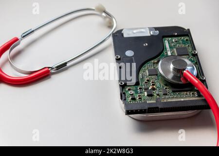 Stetoscopio rosso con unità disco rigido interna hdd contiene la cartella clinica e i dati sensibili del paziente con controllo medico hardware e riposo prima della perdita di dati in caso di guasto del sistema di archiviazione o violazione della crittografia Foto Stock
