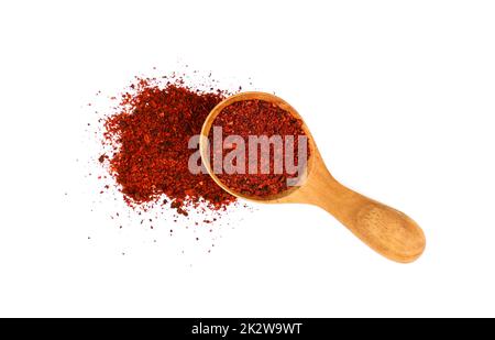 Primo piano un cucchiaio di legno pieno di pomodori secchi macinati, cumulo di polvere rovesciato, isolato su sfondo bianco, vista dall'alto elevata, terribile Foto Stock